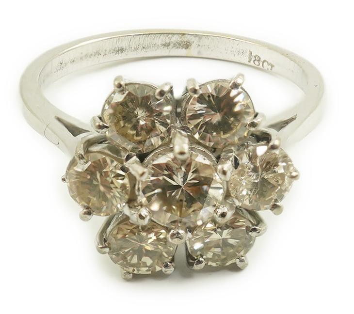 An 18ct white gold and seven stone diamond set flower head cluster ring